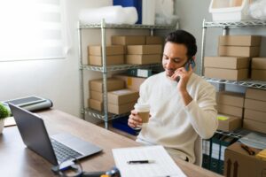 Latin,entrepreneur,multitasking,in,his,small,business,warehouse:,sipping,coffee,